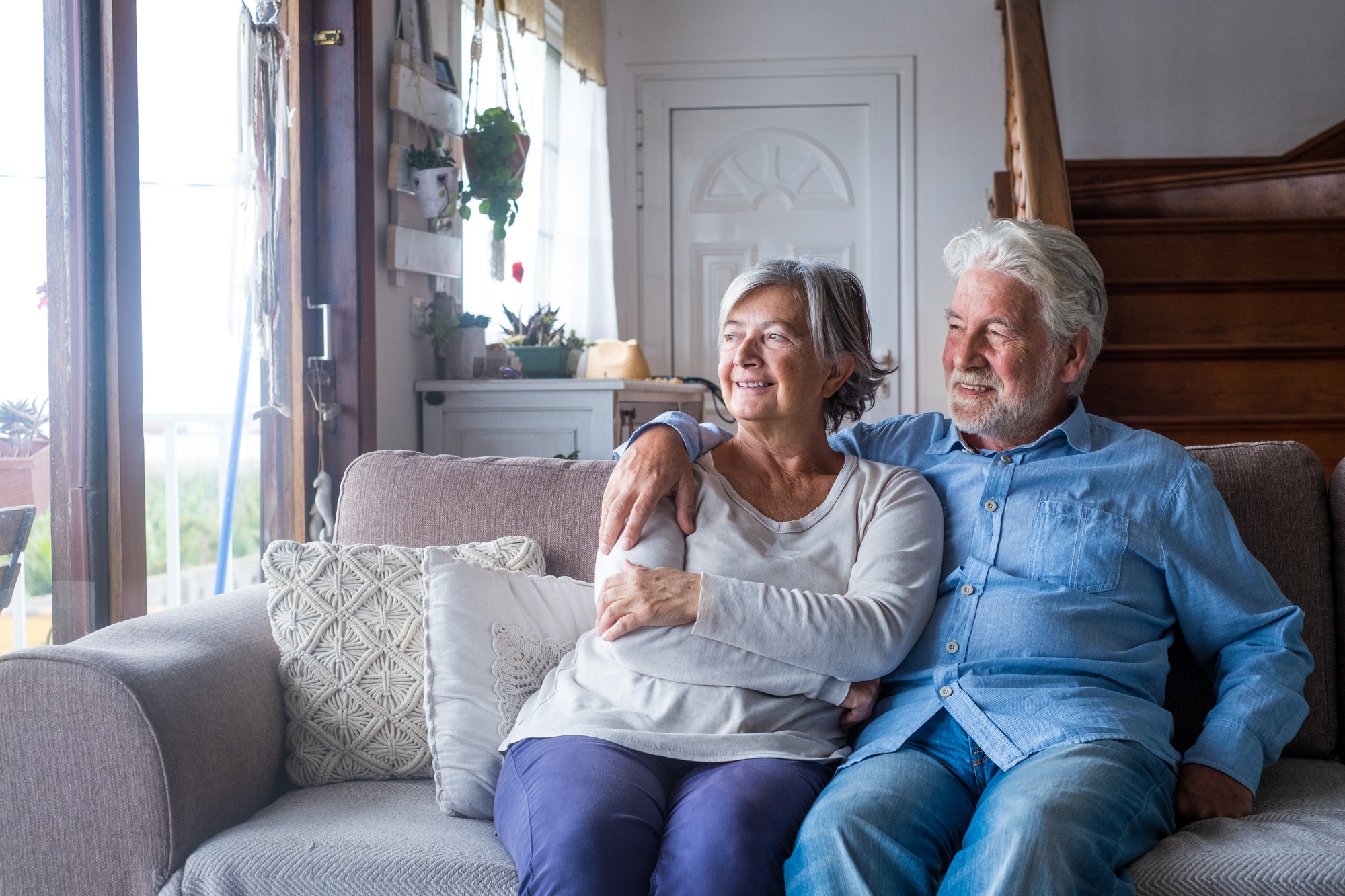 Portrait of couple of two happy and healthy seniors old people smiling and looking at the window.